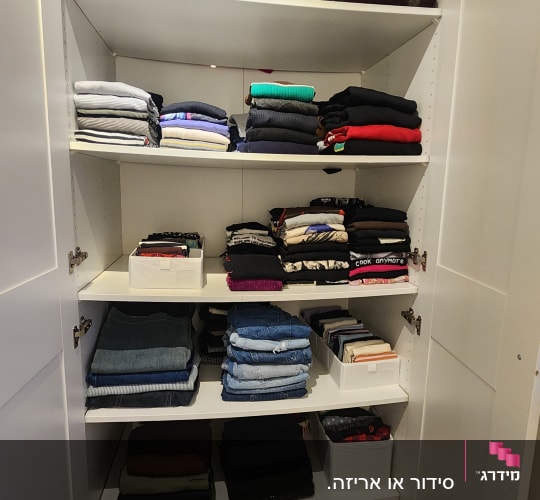 ארון בגדים מסודר עם מדפים מלאים בבגדים מקופלים